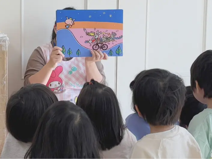 先生が人形と絵を使って子どもたちにおはなしをしている様子