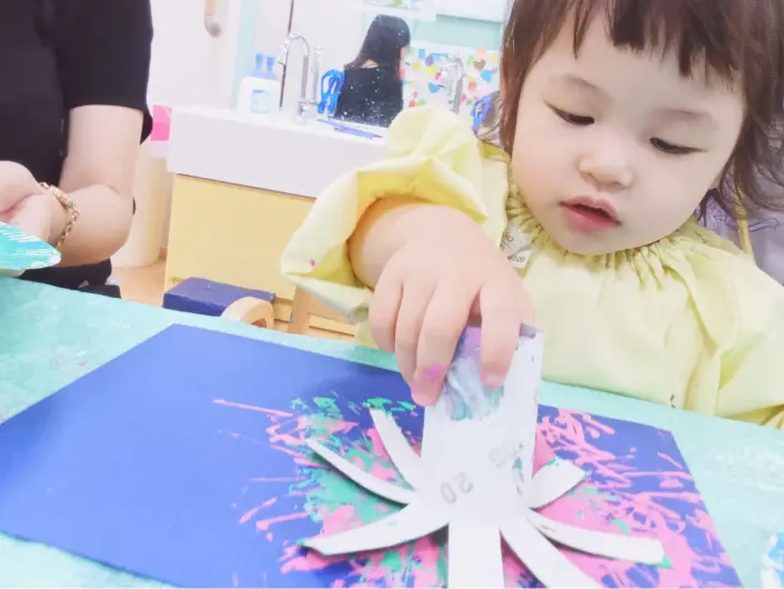 子どもが絵の具や筆を使って自由に絵を描いている様子