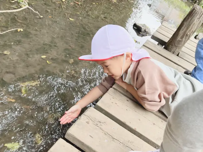 寒くなってザリガニが見つからない川で、水の温度を自分で確かめようとする子ども