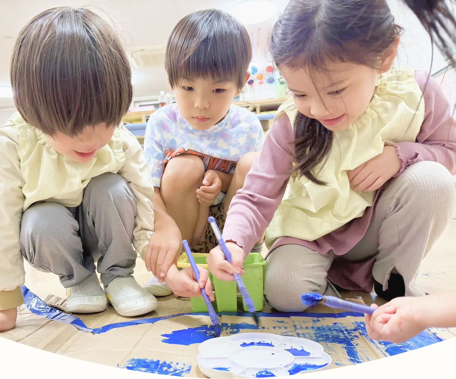 ダンボールに絵の具を塗りながら自由にものづくりを楽しむ3人の子どもたち|協力し合う中で豊かな心と生きる力を育む保育園の姿
