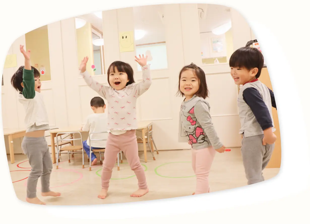 保育園の室内で手を上げて遊ぶ4人の子どもたちの笑顔|子ども第一主義を体現する保育の姿