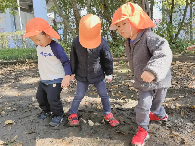 雨上がりの公園でぬるぬるした地面に気づき、感触を楽しむ子どもたちの様子