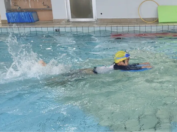 子どもたちが水泳指導を受けながらプールで楽しんでいる様子